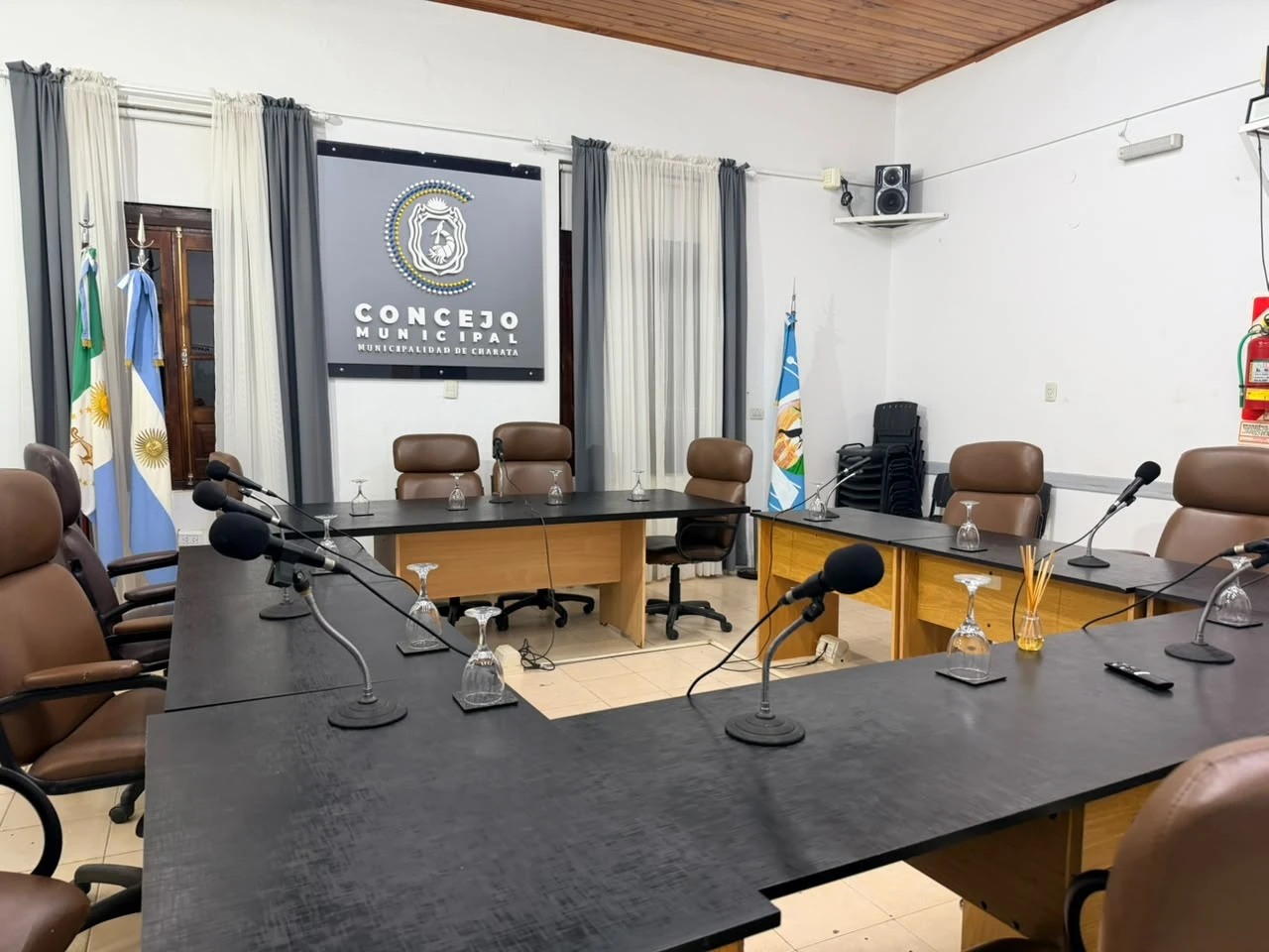 Recinto de sesiones del Concejo Municipal de Charata, con las bancas de los concejales dispuestas en U y el logo del Concejo al fondo